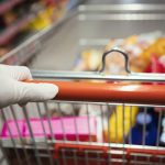 Grocery Shopping cart pushed by person with protective gloves