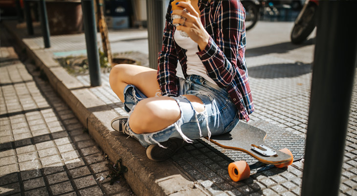 Youth on skateboard sitting on urban street