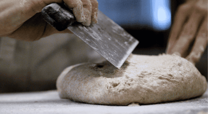 Baker working bread dough using bench knife